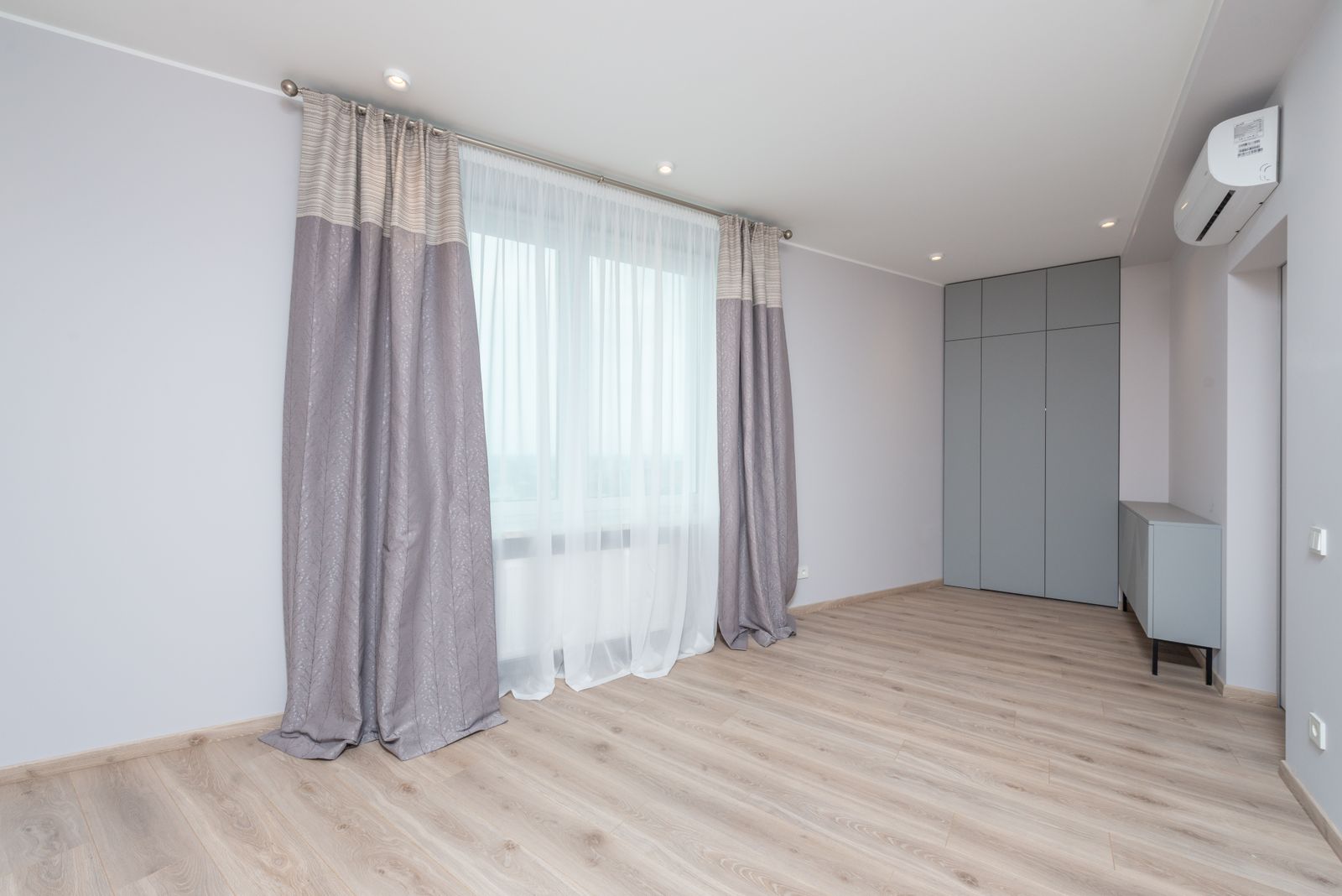 A bright modern room with a white wall-mounted split air-conditioning unit high on the right-hand wall