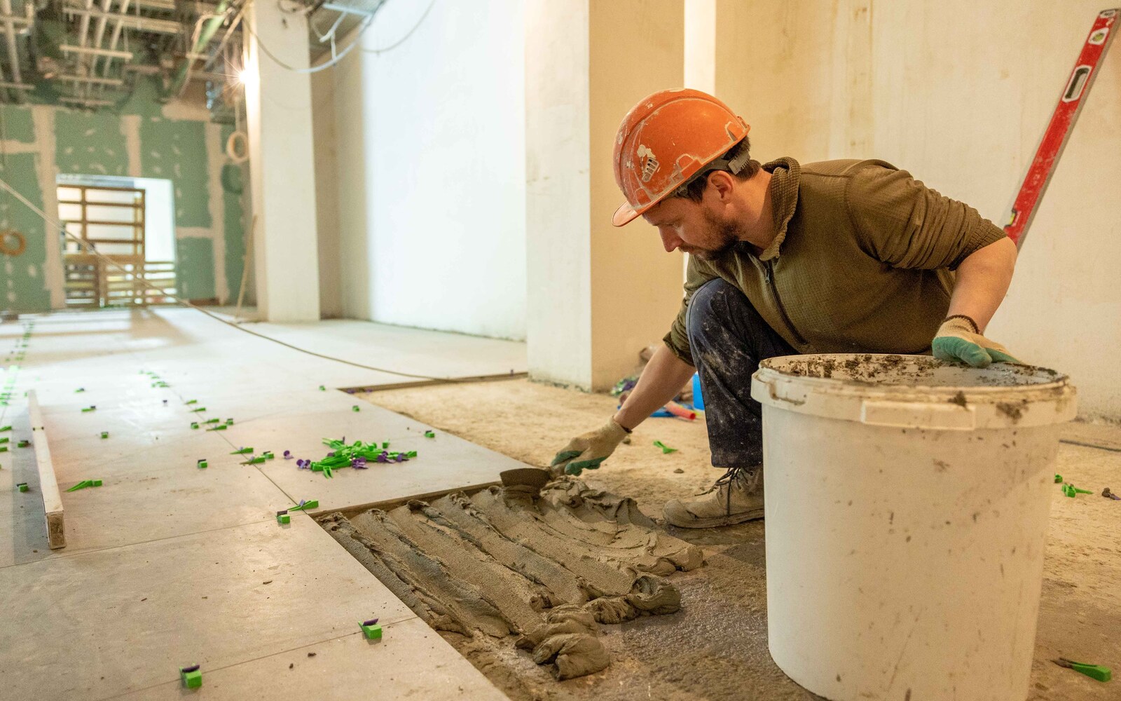 A contractor laying floor tiles during a large interior renovation