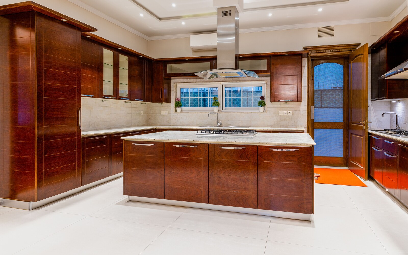 A completed fitted kitchen with an island, timber cabinets and light tiled flooring